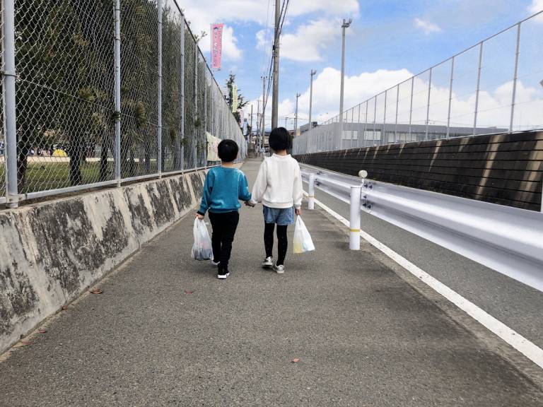 Zwei kleine Kinder gehen in Japan eine Straße entlang