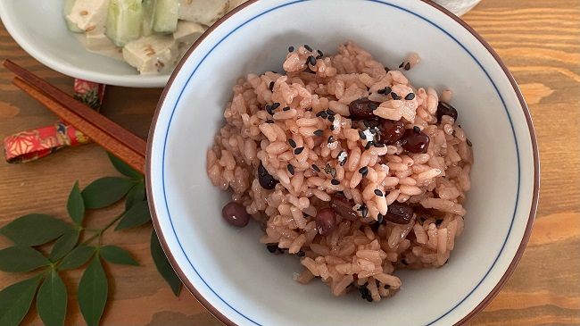 Roter Reis mit Azukibohnen serviert in kleiner Reisschüssel mit Beilage