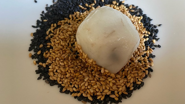 Fertige Reismehlkugel wird in weißem und schwarzem Sesam gewälzt