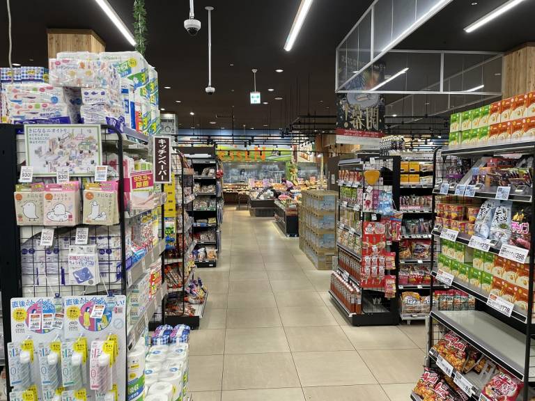 Gang im japanischen Supermarkt mit Blick auf eine Theke, über der auf Deutsch 