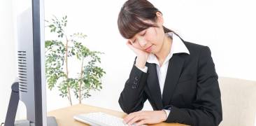 Am Computer eingeschlafene Japanerin im schwarzen Blazer