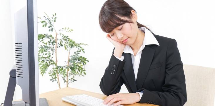 Am Computer eingeschlafene Japanerin im schwarzen Blazer