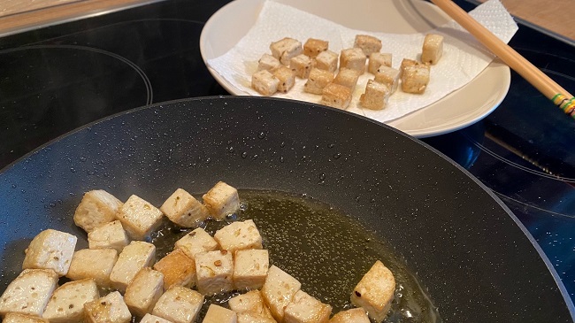 Tofuwürfel werden aus der Pfanne genommen