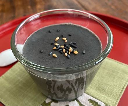 Schwarzer Sesam-Pudding in einem Glas serviert mit Sesamsamen als Topping