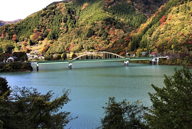 Miyama-Brücke auf dem Okutama-See mit buntem Herbstlaub im Hintergrund