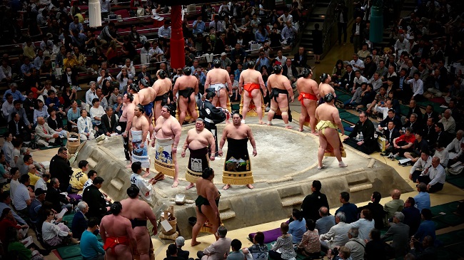 Sumo-Ringer versammeln sich vor dem Turnier um den Sumo-Ring in der voll besetzten Halle