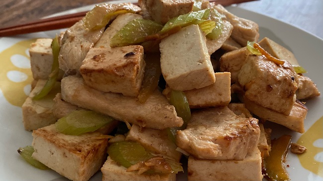 Hähnchen mit Tofu und Sellerie auf Teller mit Stäbchen serviert