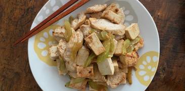 Hähnchen mit Sellerie und Tofu auf Teller mit Stäbchen serviert