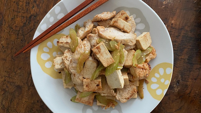 Hähnchen mit Sellerie und Tofu auf Teller mit Stäbchen serviert