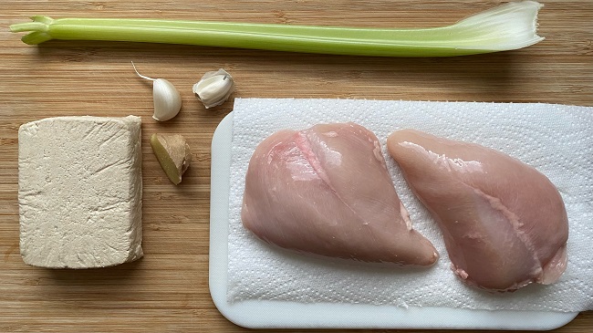 Ein Block Tofu, eine Stange Sellerie, zwei Hähnchenbrustfilets, Knoblauch und Ingwer