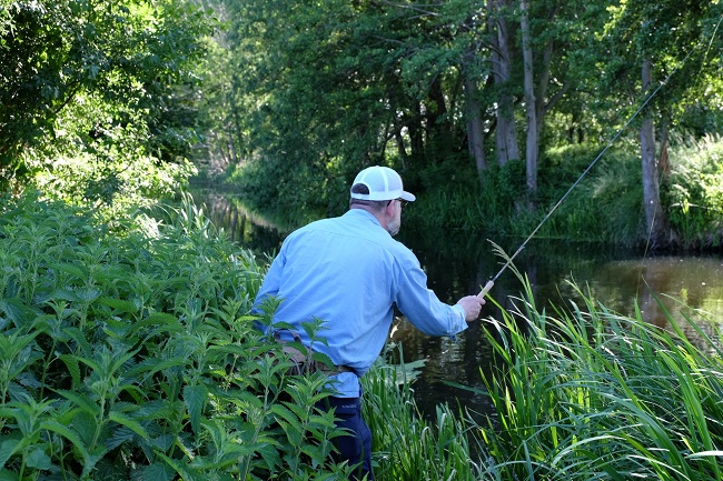 Angler im Dickicht am Flussufer