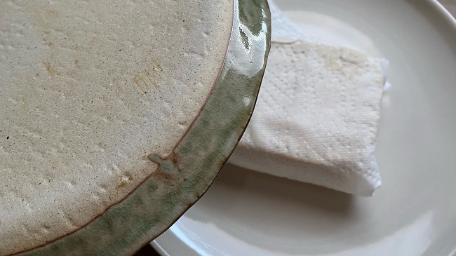 In Küchenpapier gewickelter Tofu wird mit einem Teller beschwert