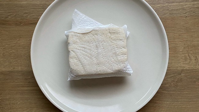 Ein Block Tofu in Küchenpapier eingewickelt