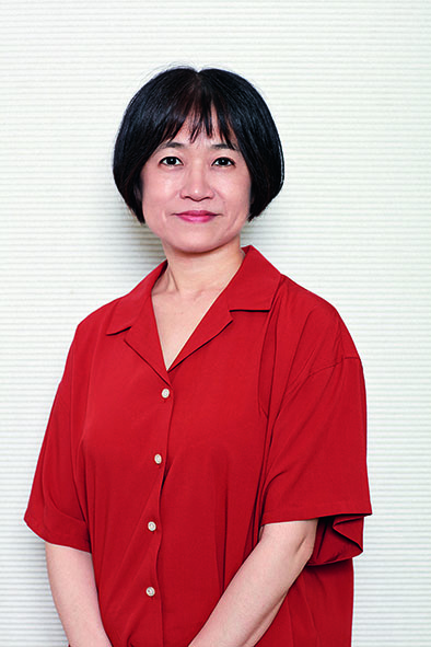 Autorin Riku Onda mit Kurzhaarschnitt und roter Bluse, lächelnd