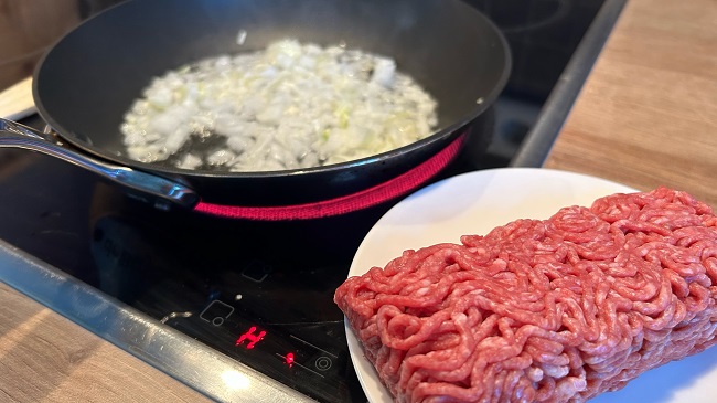 Zwiebeln braten in der Pfanne, rohes Hackfleisch auf Teller