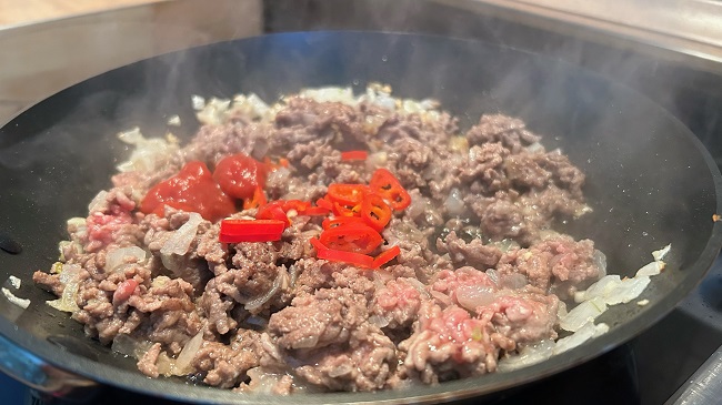 Hackfleisch, Zwiebel und Chilischote wird in der Pfanne gebraten