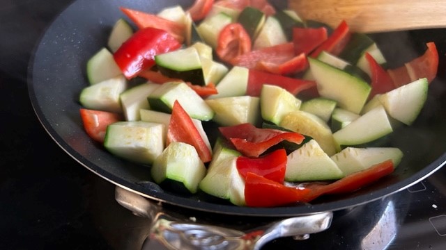 Zucchini- und Paprika-Würfel werden in der Pfanne gebraten