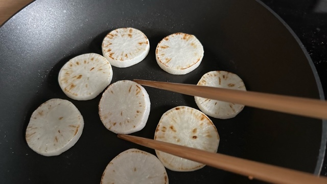 Rettichscheiben werden mit Stäbchen in der Pfanne gewendet