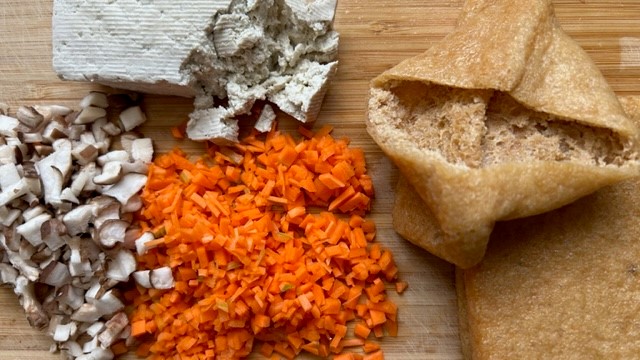 Kleingeschnittene Shiitake-Pilze und Karotte sowie teils zerbröckelter Tofu