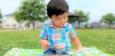 Junge liest im Park ein Bilderbuch