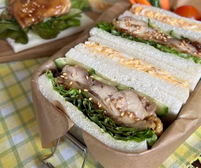 Eier- & Teriyaki-Sandwiches in Bento-Box auf kariertem Tuch serviert