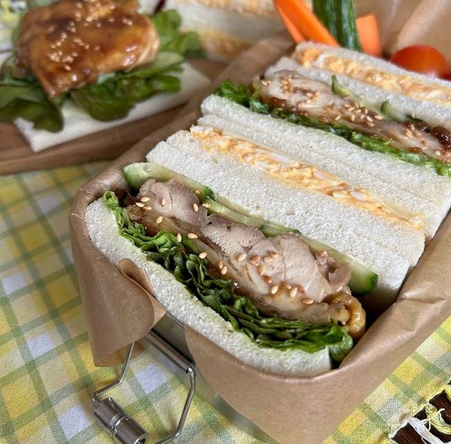Eier- & Teriyaki-Sandwiches in Bento-Box auf kariertem Tuch serviert