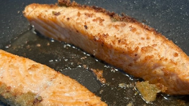 Paniertes Lachsfilet wird von beiden Seiten gebraten