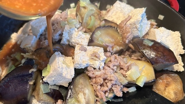 Miso-Mischung wird zu Tofu, Gemüse und Hackfleisch in die Pfanne gegeben