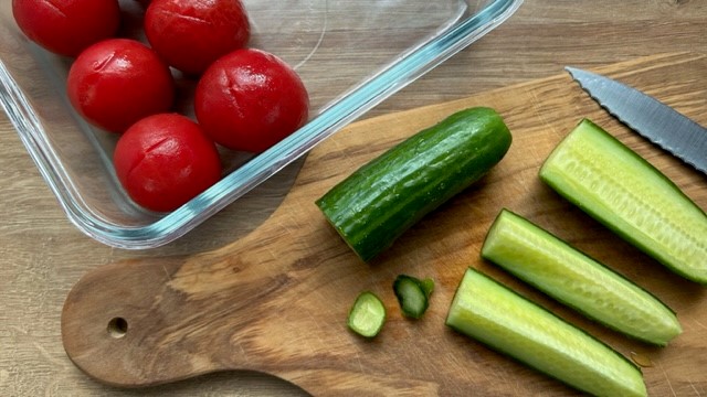 Cocktailtomaten in Glasform, Gurke auf dem Holzbrett in Streifen geschnitten