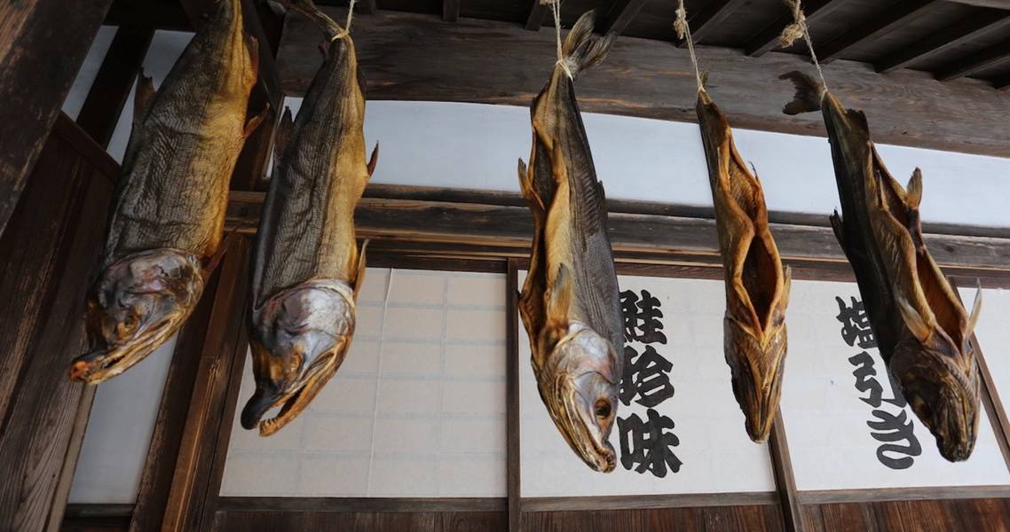 Unter dem Vordach hängende Lachse in der Stadt Murakami.