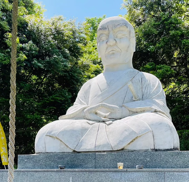 Statue von Miyamoto Musashi mit Bäumen im Hintergrund