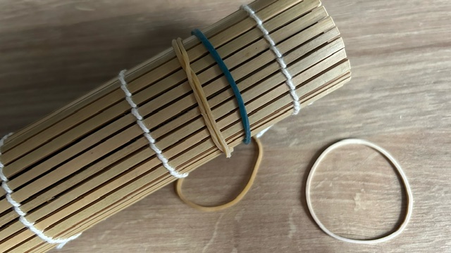 Teigrolle in Bambusmatte gehüllt und mit Gummibändern fixiert