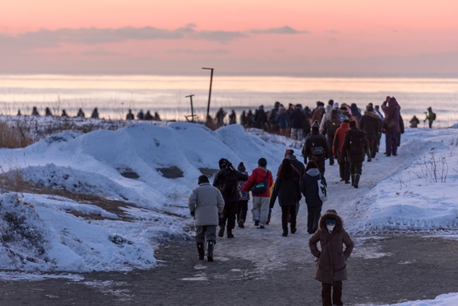 Menschenmengen strömen vor Sonnenaufgang an den mit Schnee bedeckten Strand