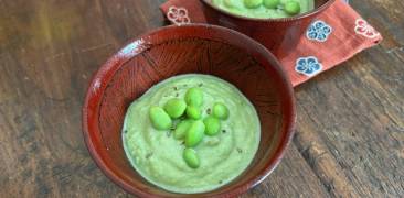 Edamame-Suppe in zwei Schälchen mit Stoff-Unterlagen