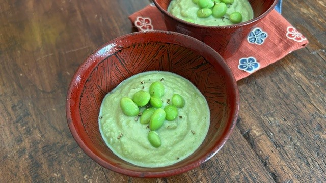 Edamame-Suppe in zwei Schälchen mit Stoff-Unterlagen