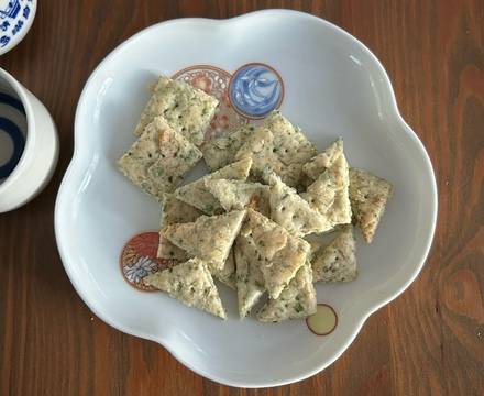 Fertige Ebi-senbei (Garnelen-Cracker) auf Teller serviert mit Sake-Bechern