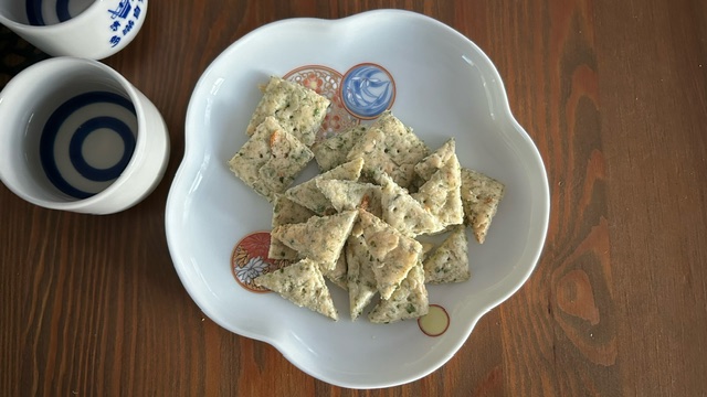 Fertige Ebi-senbei (Garnelen-Cracker) auf Teller serviert mit Sake-Bechern