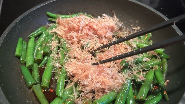 Bonito-Flocken werden in die Pfanne gegeben und mit Paprika-Flocken vermischt