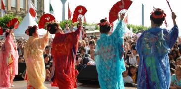 Japanerinnen tanzen mit roten Fächern in bunten Gewändern