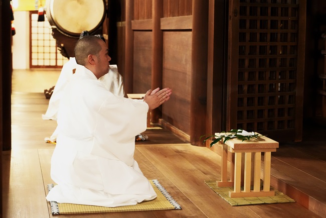 Mann kniet im weißen Gewand betend in einem Schrein