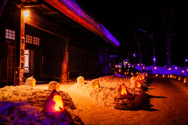 Erleuchtete Mini-Schneehäuser vor einem Holzhaus