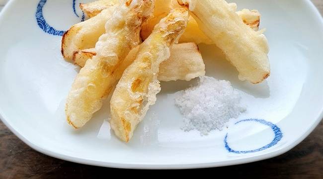 Spargel-Tempura mit einem Häufchen Salz auf weißen Teller mit blauem Muster serviert