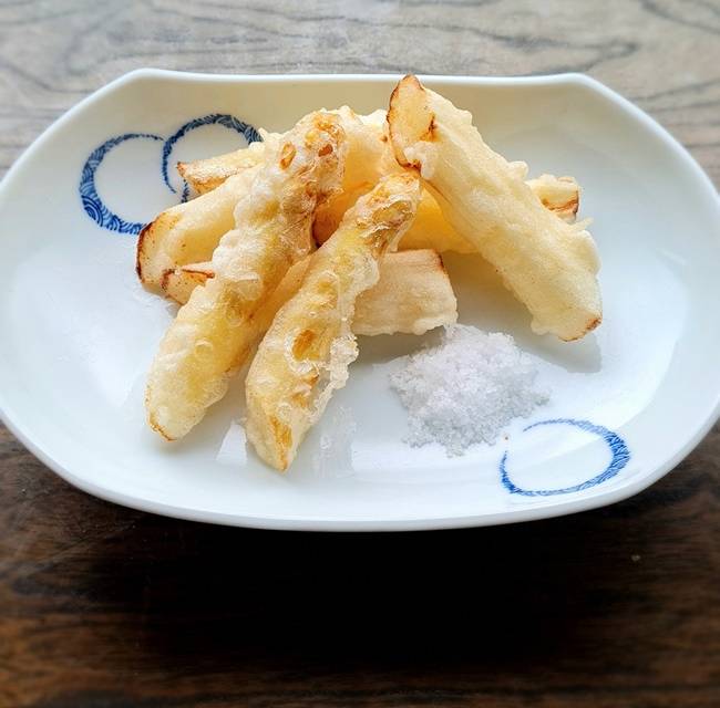 Spargel-Tempura mit einem Häufchen Salz auf weißen Teller mit blauem Muster serviert