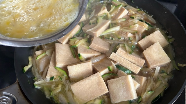 Verquirlte Eier werden zu Tofu und Gemüse in die Pfanne gegeben