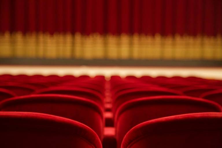 Kinosaal mit roten Sitzen und rot-goldenem Vorhang